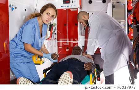 Paramedic team providing first aid to man Paramedic team providing first aid to man 76037972
