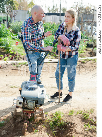 Man and woman gardeners standing near plow before using Man and woman gardeners standing near plow before using 76038155