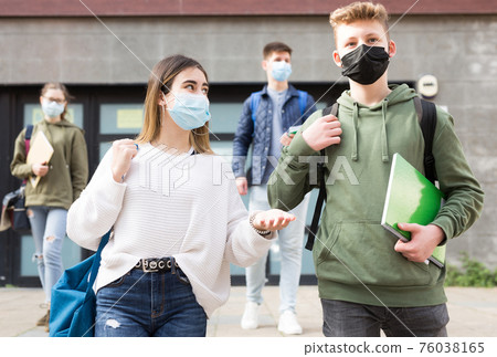 Teenagers in masks walking after lessons Teenagers in masks walking after lessons 76038165