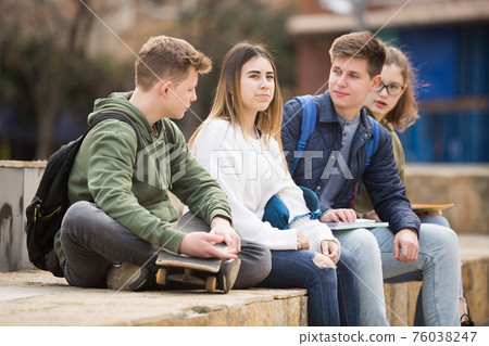 Company of teenagers are communicating on walk on street Company of teenagers are communicating on walk on street 76038247
