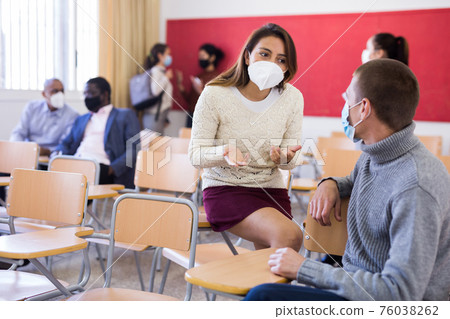 Students in protective masks are talking about homework at desk Students in protective masks are talking about homework at desk 76038262