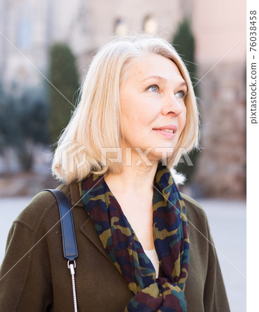 Elegant mature woman is posing in time walking on the street of old city Elegant mature woman is posing in time walking on the street of old city 76038458