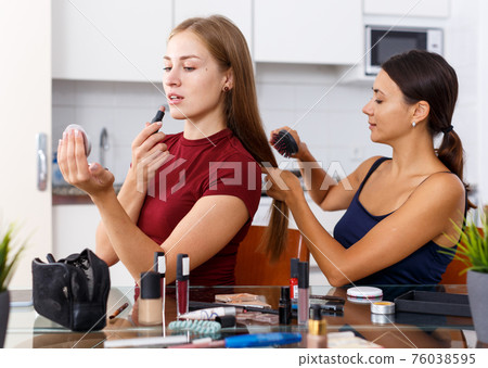 Attractive young female doing make up and girlfriend combing her hair 76038595