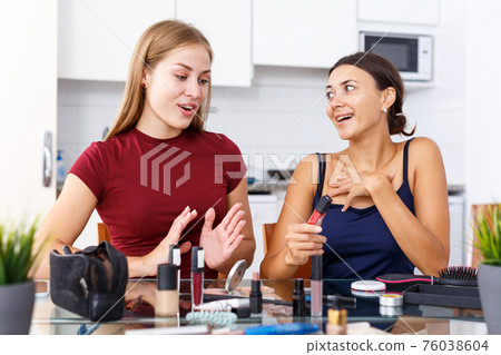 Female friends applying cosmetics 76038604