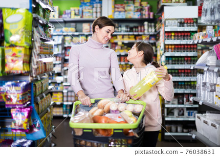 Young mother with daughter choosing refreshing beverages in supermarket Young mother with daughter choosing refreshing beverages in supermarket 76038631