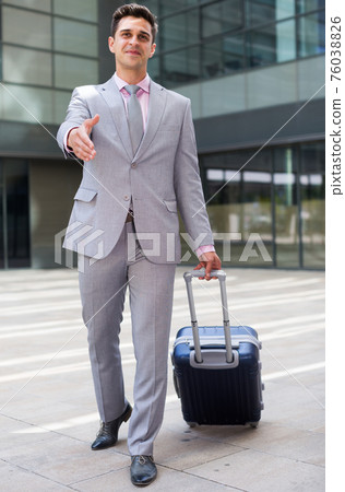 Businessman with suitcase offering handshake 76038826