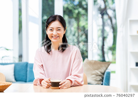Middle woman drinking coffee in the dining room 76040297