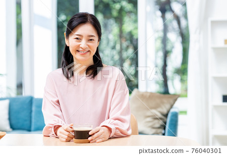Middle woman drinking coffee in the dining room 76040301