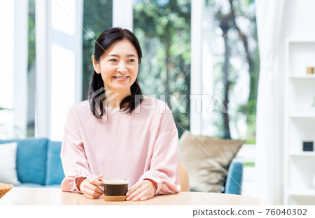 Middle woman drinking coffee in the dining room 76040302