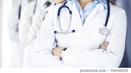 Group of modern doctors standing as a team with arms crossed in hospital office. Medical help, insurance in health care, best desease treatment and medicine concept Group of modern doctors standing as a team with arms crossed in hospital office. Medical help, insurance in health care, best desease treatment and medicine concept 76040928
