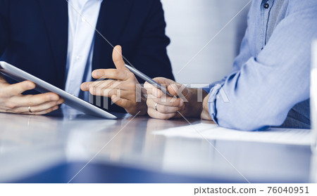 Business people using tablet computer while working together at the desk in modern office. Unknown businessman or male entrepreneur with colleague at workplace. Teamwork and partnership concept 76040951