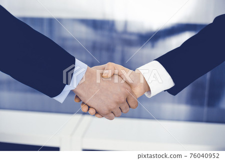 Businessman and woman shaking hands in office. Concept of handshake as success symbol in business Businessman and woman shaking hands in office. Concept of handshake as success symbol in business 76040952