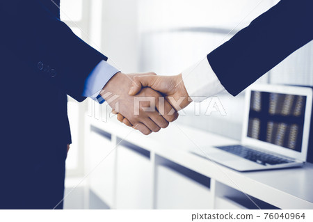 Businessman and woman shaking hands in office. Concept of handshake as success symbol in business Businessman and woman shaking hands in office. Concept of handshake as success symbol in business 76040964