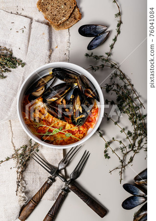 Food still life. Mussels with vegetables, linen napkin, vintage forks and oregano sprigs on a light background. Delicious and healthy traditional seafood. Shellfish. Top view Food still life. Mussels with vegetables, linen napkin, vintage forks and oregano sprigs on a light background. Delicious and healthy traditional seafood. Shellfish. Top view 76041084