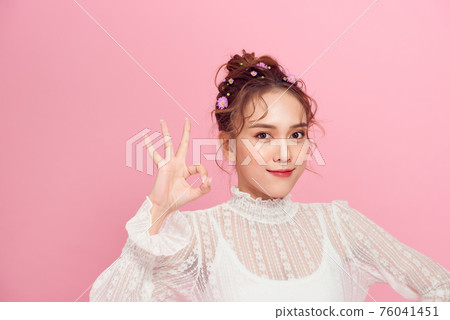 Happy young woman showing ok sign with fingers an winking isolated on a pink background Happy young woman showing ok sign with fingers an winking isolated on a pink background 76041451