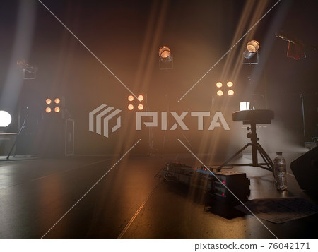 Concert stage and lighting fixtures on it, musical equipment. Smoke from a smoke installation gently breaks yellow light and creates the effect of a gentle glow. Concert stage and lighting fixtures on it, musical equipment. Smoke from a smoke installation gently breaks yellow light and creates the effect of a gentle glow. 76042171