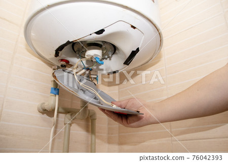 The boiler repair technician uses an adjustable wrench to unscrew or tighten the nut on the pipe. Installing a water heater or dismantling a damaged boiler for later repair. 76042393