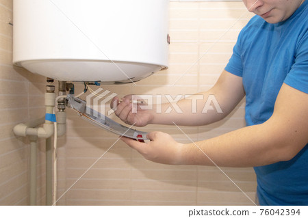 The boiler repair technician uses an adjustable wrench to unscrew or tighten the nut on the pipe. Installing a water heater or dismantling a damaged boiler for later repair. The boiler repair technician uses an adjustable wrench to unscrew or tighten the nut on the pipe. Installing a water heater or dismantling a damaged boiler for later repair. 76042394
