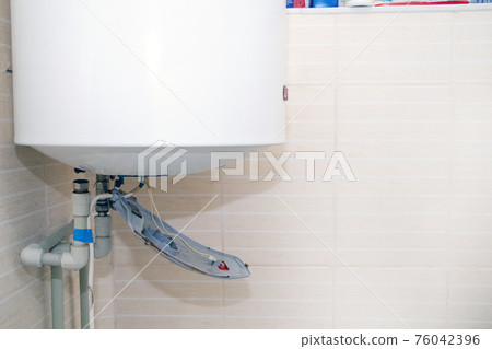 The boiler repair technician uses an adjustable wrench to unscrew or tighten the nut on the pipe. Installing a water heater or dismantling a damaged boiler for later repair. 76042396