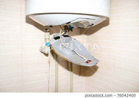 The boiler repair technician uses an adjustable wrench to unscrew or tighten the nut on the pipe. Installing a water heater or dismantling a damaged boiler for later repair. 76042400