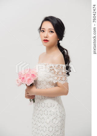 Young beautiful pretty Asian girl standing and holding pink roses over white background. Young beautiful pretty Asian girl standing and holding pink roses over white background. 76042474