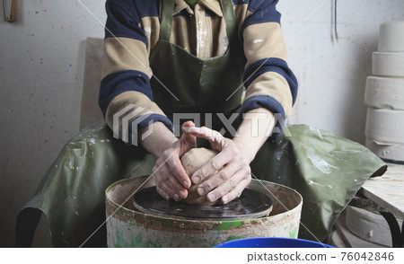 Hands of a potter on a pottery wheel close-up. Old traditional art, handmade, clay and ceramic production. Pottery workshop in subdued soft light Hands of a potter on a pottery wheel close-up. Old traditional art, handmade, clay and ceramic production. Pottery workshop in subdued soft light 76042846