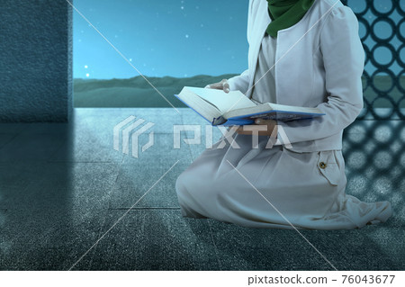 Muslim woman in a veil sitting and reading the Quran Muslim woman in a veil sitting and reading the Quran 76043677