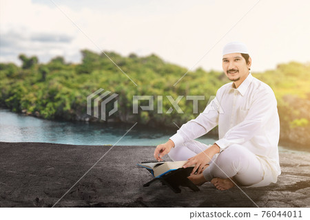 Asian Muslim man sitting and reading the Quran 76044011