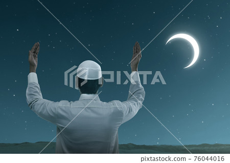 Asian Muslim man standing while raised hands and praying Asian Muslim man standing while raised hands and praying 76044016