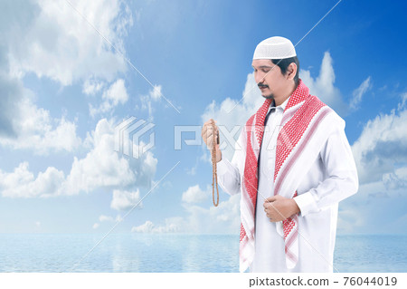 Asian Muslim man praying with prayer beads on his hands 76044019