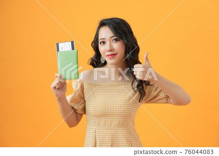 Woman over isolated yellow background in vacation holding a passport and plane with thumb up Woman over isolated yellow background in vacation holding a passport and plane with thumb up 76044083