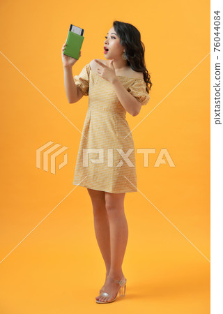 Tourist woman on vacation holding passport very happy pointing with hand and finger Tourist woman on vacation holding passport very happy pointing with hand and finger 76044084