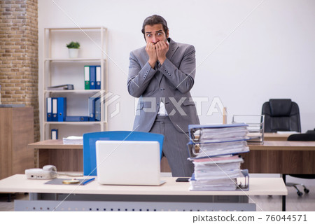 Young male employee unhappy with excessive work in the office Young male employee unhappy with excessive work in the office 76044571
