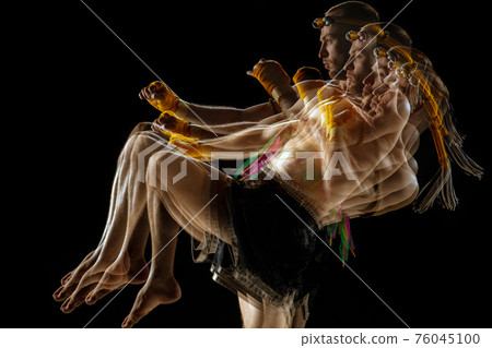 Young man thai boxer training over dark background in neon mixed light. 76045100