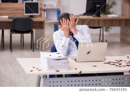 Young male employee and too many cockroaches in the office 76045395