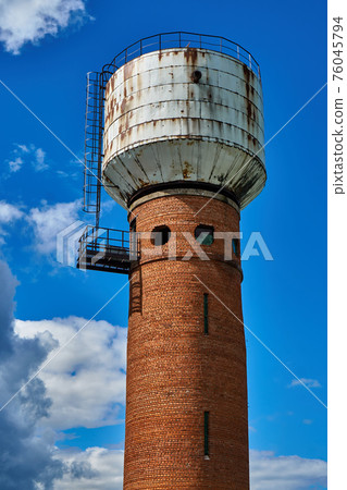 Water tower made of brick and metal with round windows Water tower made of brick and metal with round windows 76045794