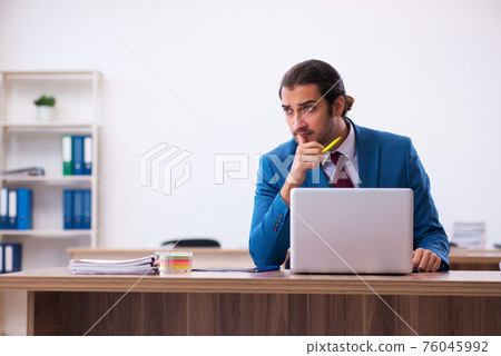 Young male employee working at workplace Young male employee working at workplace 76045992