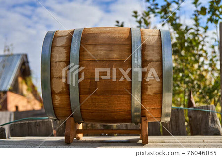 Oak barrel for storage wine lies on special support in yard Oak barrel for storage wine lies on special support in yard 76046035