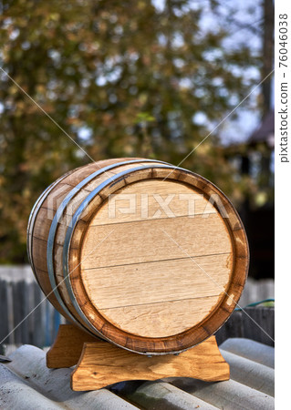 Oak barrel for storage wine lies on special support in yard Oak barrel for storage wine lies on special support in yard 76046038