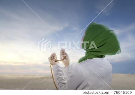 Asian Muslim woman in veil praying with prayer beads on her hands 76046109