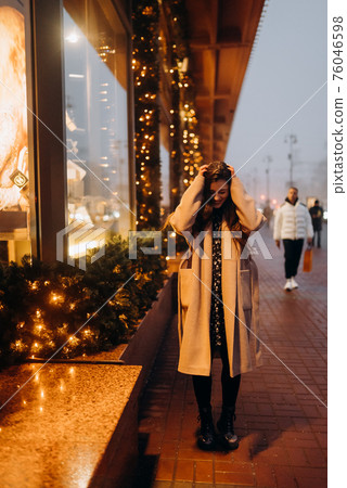 Woman by illuminated showcase on city street. 76046598