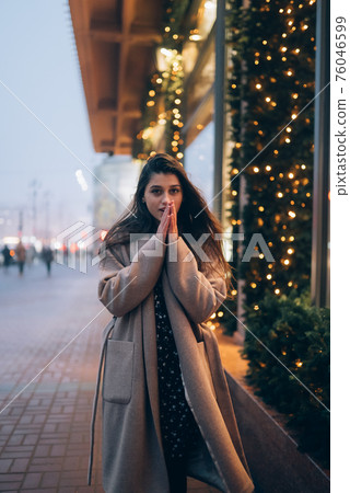 Woman by illuminated showcase on city street. 76046599