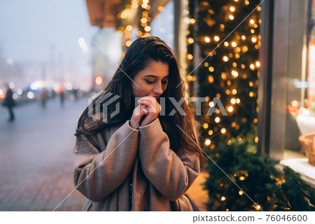 Woman by illuminated showcase on city street. 76046600