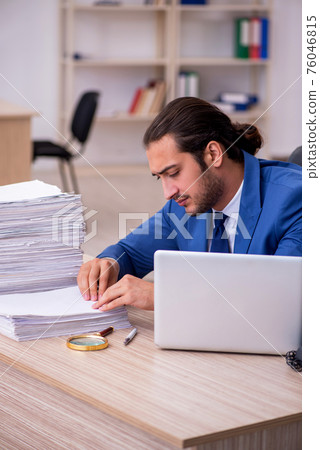 Young male employee and too much work in the office 76046815