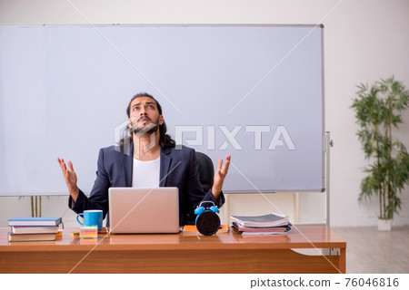 Young male teacher in the classroom 76046816