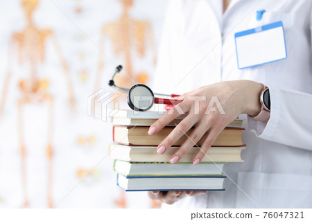 Doctor hands are holding stack of books and stethoscope 76047321