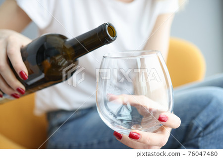 Woman hand pours wine into large glass Woman hand pours wine into large glass 76047480
