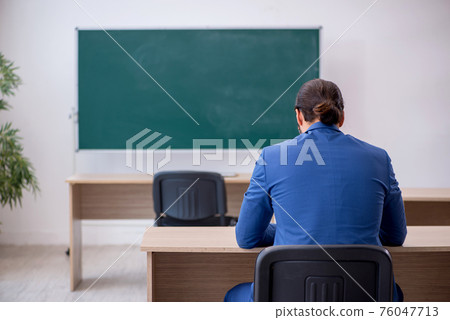 Young male teacher in suit in front of green board Young male teacher in suit in front of green board 76047713