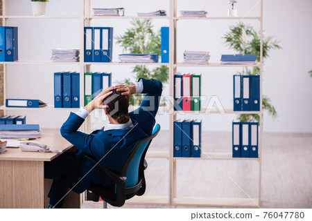 Young male employee and too many work in the office Young male employee and too many work in the office 76047780