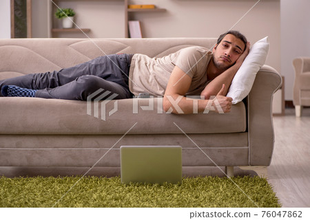 Young man lying on the sofa at home Young man lying on the sofa at home 76047862